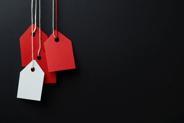 Poster - Red and white blank price tags hanging on black background with copy space