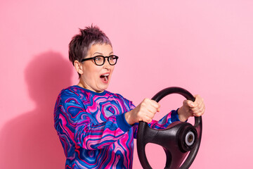 Sticker - Photo of attractive senior woman scared accident hold steering wheel dressed blue colorful clothes isolated on pink color background