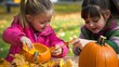 © Felippe Lopes - Two young girls decorate pumpkins with fall leaves, a festive fall activity.