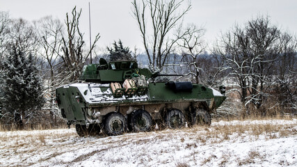 A green military vehicle is parked in a snowy field