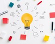 © sorrakrit - A light bulb surrounded by sticky notes, pens, and drawings on a white surface, representing creativity and inspiration.