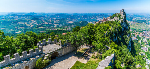 Wall Mural - A panorama view over the ramparts of the second tower towards the first tower in the fortified section of San Marino, Italy in summertime