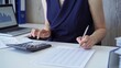 © volha_r - Businesswoman with dark blue dress is using dark calculator and taking notes of company expenses in her office. Taxes and audit in business