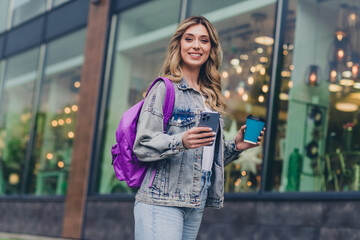 Poster - Photo of nice young woman hold phone coffee backpack wear denim jacket walk city center outdoors