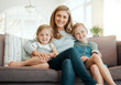 © KayJoint/peopleimages.com - Mother, girls portrait and relax on couch together, hug and parent to love children in home. Mama, daughter and kids in embrace for security in relationship, care and bonding for connection in Canada