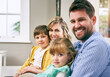© peopleimages.com - Family, portrait and smile in house for relax, bonding and support with parents, love and care. Mom, dad and children in living room for comfort, relationship and embrace together on weekend on sofa