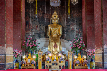 Thailand, August 11, 2024, Wat Kanlayanamit Woramahawihan, Golden Buddha statue in an ornate temple with chandeliers and mural paintings during afternoon light