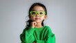 © K-MookPan - A thoughtful child in vibrant green clothing, wearing stylish glasses and posing confidently with a charming expression.