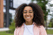 © Liubomir - Confident African American female student with curly hair and glasses smiling warmly outdoors. Captures essence of youth and education, highlighting positive attitude and friendly demeanor