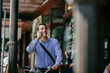 © Marko Geber - Middle aged businessman with smartphone commuting in city with bike