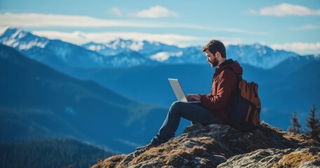Poster - A young man works on a laptop while sitting at the top of a mountain. This concept represents the digital nomad lifestyle and the ability to work remotely or travel using the internet.