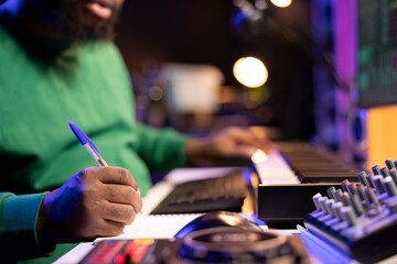 Wall Mural - Songwriter taking notes to create new tracks for an album in his home studio, writing lyrics and harmonic elements before recording his song and editing on software, acoustical engineering.