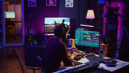 Music producer mixing individual tracks into a stereo in home studio, artist adjusting levels, panning and special effects to achieve a balanced audio. Musician does acoustical engineering. Camera A.