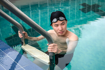 Professional male swimmer holding stairs in pool