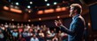 © indyntk - Powerful visual of a public speaker commanding attention with assertive body language and confident gestures on a stage with an engaged audience