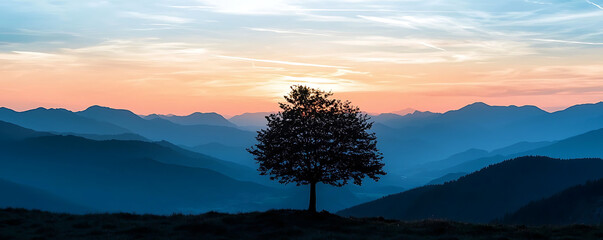 Wall Mural - A breathtaking view of a solitary tree's silhouette standing against the backdrop of a vivid sunset over mountain ranges