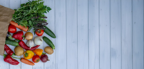 fresh vegetables and paper bag on white wooden background. Selective focus