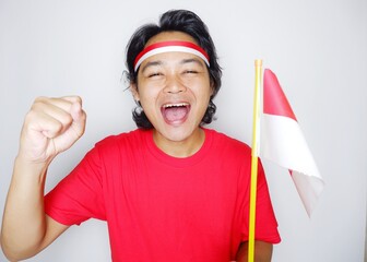 Portrait of an Indonesian man with long hair with a headband and red shirt celebrating Indonesian Independence Day with high nationalism on an isolated white background