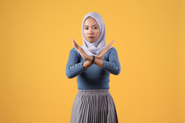 asian indonesian muslim woman showing X sign no hand gesture on isolated yellow background