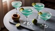 © Kartik - Flat lay with margarita cocktails with pieces of lime, ice cubes and wooden squeezer on grey tabletop
