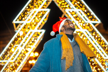 African man in Santa Hat in a Christmas city night