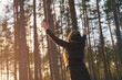 © GCapture - teen girl raised hands from behind in winter pine forest in sunset
