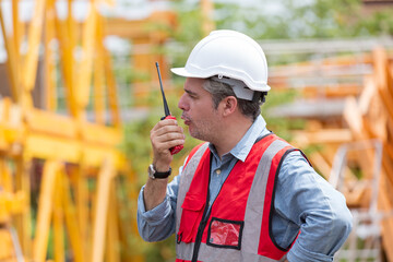 Male construction working at construction site. Male engineer using walkie talkie at work site. Male engineer construction wear safety uniform and helmet at construction site