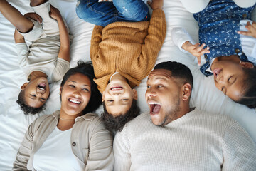 Canvas Print - Parents, children and above bed with laughing, love and funny memory for connection in morning at family house. Father, mother and kids with lying, excited and happy for comic joke at apartment