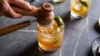 © Kartik - Close up view of wooden squeezer, refreshing sour caipirinha cocktails with lime and ice on grey tabletop