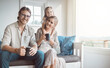 © CourtH/peopleimages.com - Portrait, happy and parents with child on sofa for bonding, loving relationship and relax together in morning. Family, coffee and mom, dad and girl on couch for love, laugh and embrace in living room