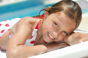 close up of little cheerful girl lying down by the swimming pool 