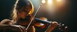 © pentolo - A young woman with closed eyes plays the violin on stage under warm spotlights.