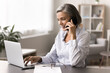 © fizkes - Mature businesswoman engaging in conversation on phone while working on laptop, contact with support customer services, placing order, discuss purchase, lead talk to client, solve business remotely