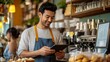 © The Little Hut - Young barista cafe owner multiracial male holding tablet taking coffee and bakery orders from female Asian customer creamcolored shirt front of cash register counter of small cafe smal : Generative AI