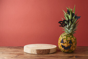 Poster - Halloween holiday concept with jack o lantern pineapple and empty wooden log  on wooden table. Mock up for design and product display