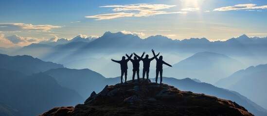 Silhouettes of Four Hikers on a Mountain Peak at Sunset