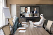 © fizkes - Team of Arab business colleagues talking to diverse foreign partners, employees on video conference call, sitting at office meeting table in boardroom, looking at electronic board with headshots