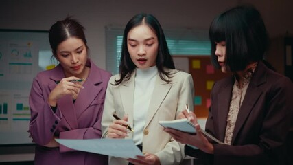 Poster - Three young businesswomen collaborate in an office setting, reviewing documents and brainstorming ideas during a productive working session focused on strategy and planning