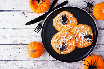 Aufkleber - Fun Halloween spider web pumpkin pancakes with blackberry spiders. Overhead view on a black plate against a rustic white wood table background.