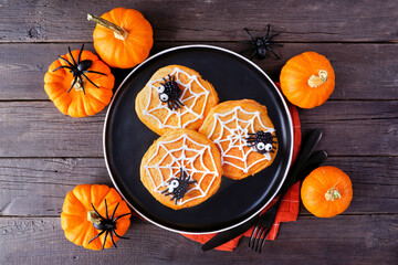 Aufkleber - Spooky Halloween spider web pumpkin pancakes with blackberry spiders. Top view on a black plate against a dark wood table background.