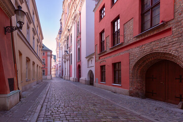 Wall Mural - A deserted narrow cobblestone street in the center of Poznan at dawn.