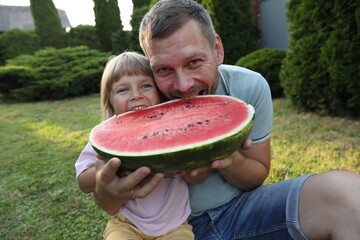 Poster - Man and his cute daughter eating juicy watermelon outdoors together