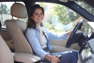 Wall Mural - Smiling woman holding steering wheel while driving car