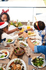 Wall Mural - Parents, kids and cheers with food on Christmas at table on patio for lunch and celebration at home. People, family and above for festive season or holiday for gathering, support and love with smile