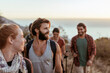 © Marko Geber - Group of friends smiling while hiking on a mountain trail at sunset
