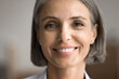 © fizkes - Portrait of happy beautiful middle-aged 50s woman with short haircut looking at camera, close up cropped face view on abstract background. Rejuvenating skin care products, dental clinic services ad