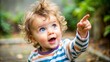 © Sirinporn - Adorable curious toddler with bright curious eyes and messy hair, enthusiastically pointing finger at something off-camera, conveying excitement and discovery.