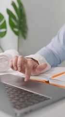 Aufkleber - An individual is focused on using a laptop and making notes in a notebook, indicating they are likely in a professional or academic environment, concentrating on tasks and responsibilities