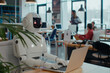 © ToveStock - Humanoid robot working on a laptop in a modern office environment, surrounded by professionals, integration of ai and robotics in the workplace