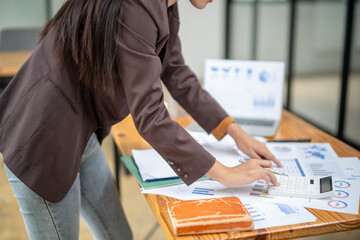 Leinwandbilder - A woman is sitting at a desk with a calculator and a stack of papers